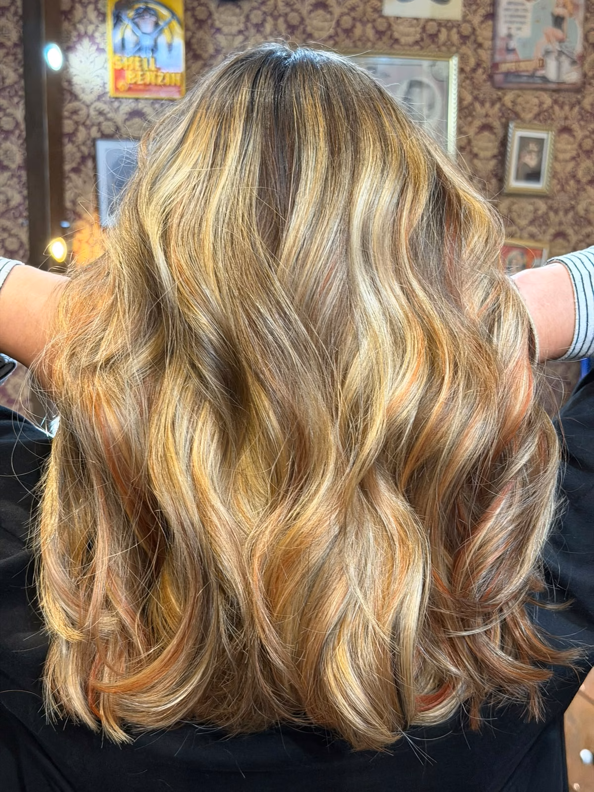 Warme Karamell-Balayage mit blonden Strähnen und Wellen von hinten