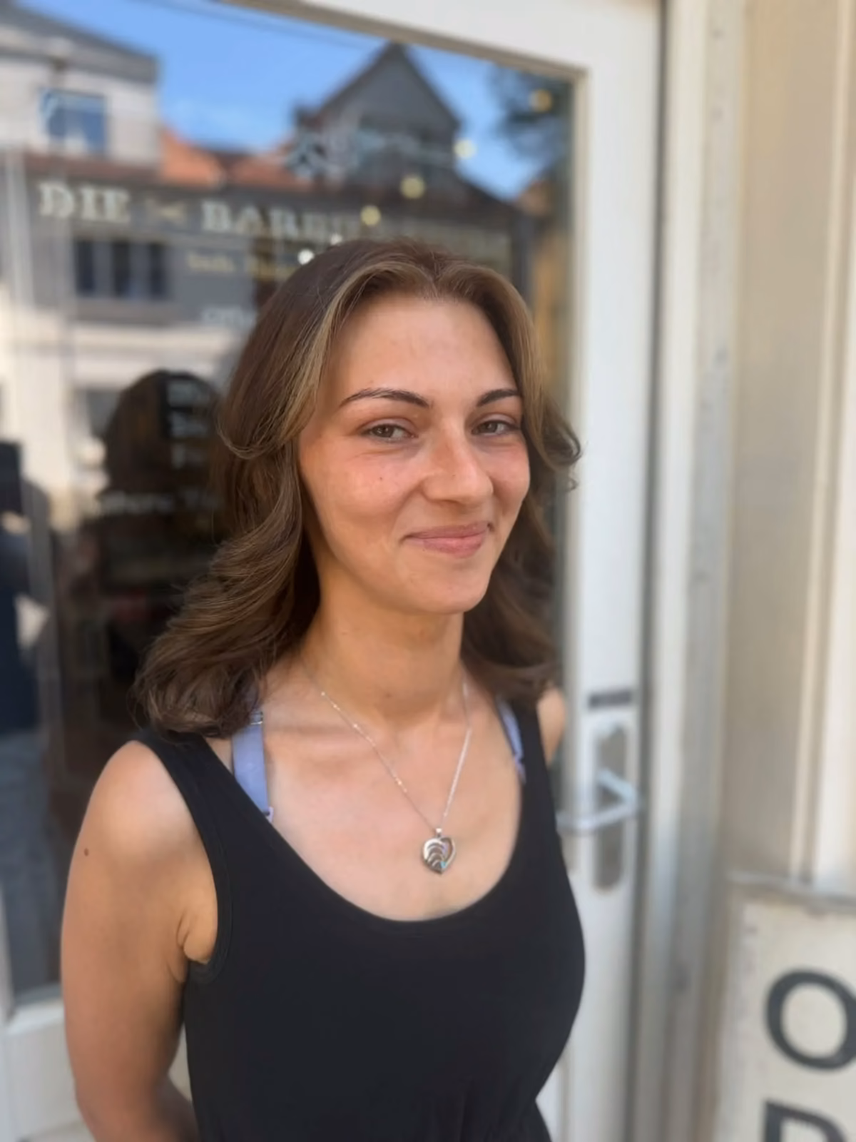 Kundin mit gewellten Haaren vor dem Salon